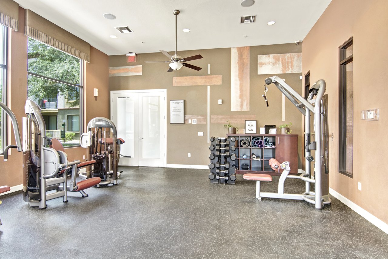 Gym with weight machines, free weights, and yoga mats