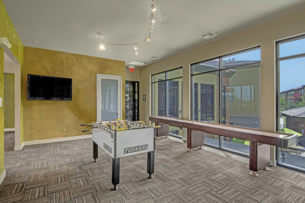 Community game room with foosball and shuffleboard tables and a TV.