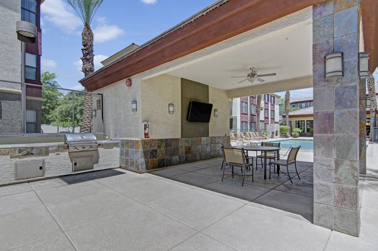 Outdoor kitchen and seating area by the pool with lounge chairs.