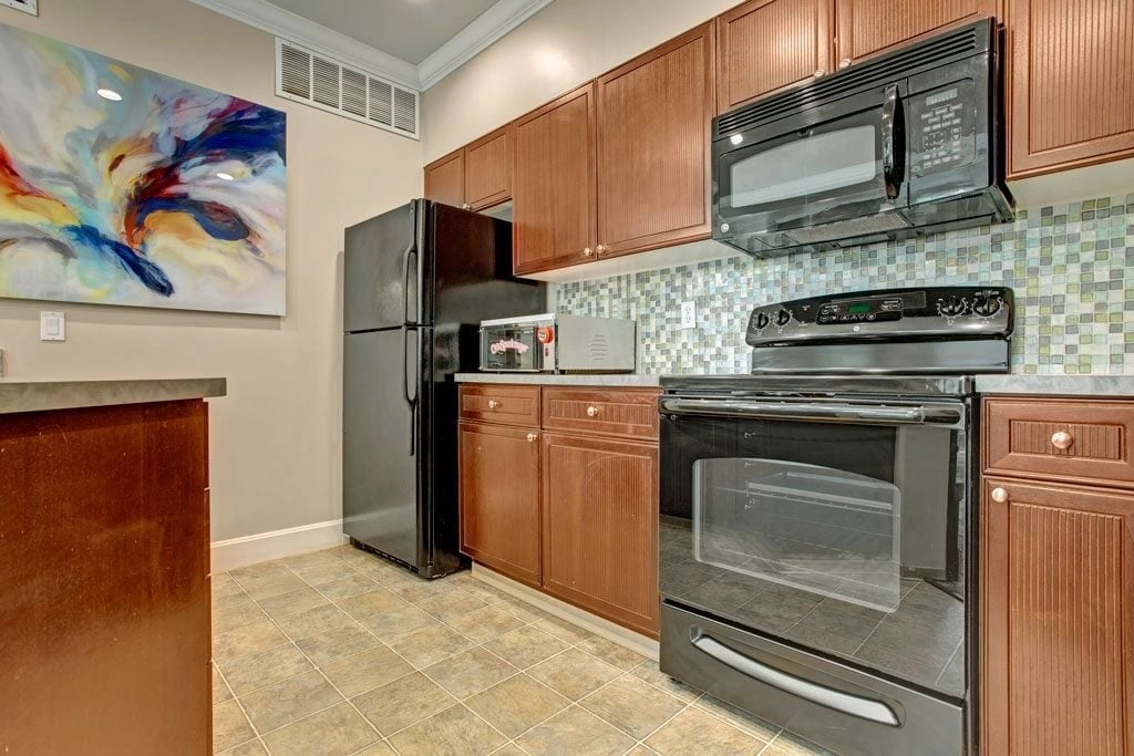Kitchen with dark wood cabinets, black appliances, and modern tile backsplash.