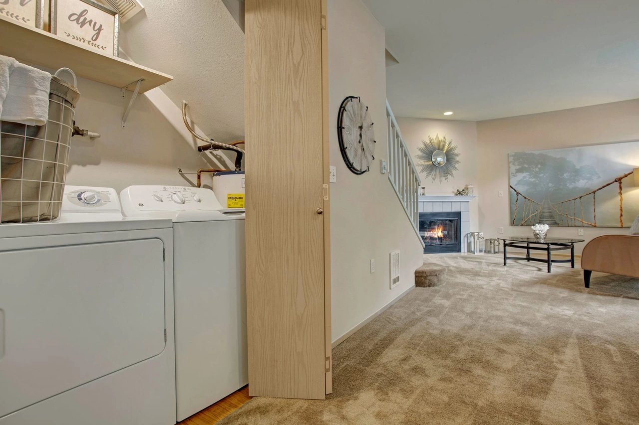 Stackable washer and dryer in a laundry room with shelves and a water heater.