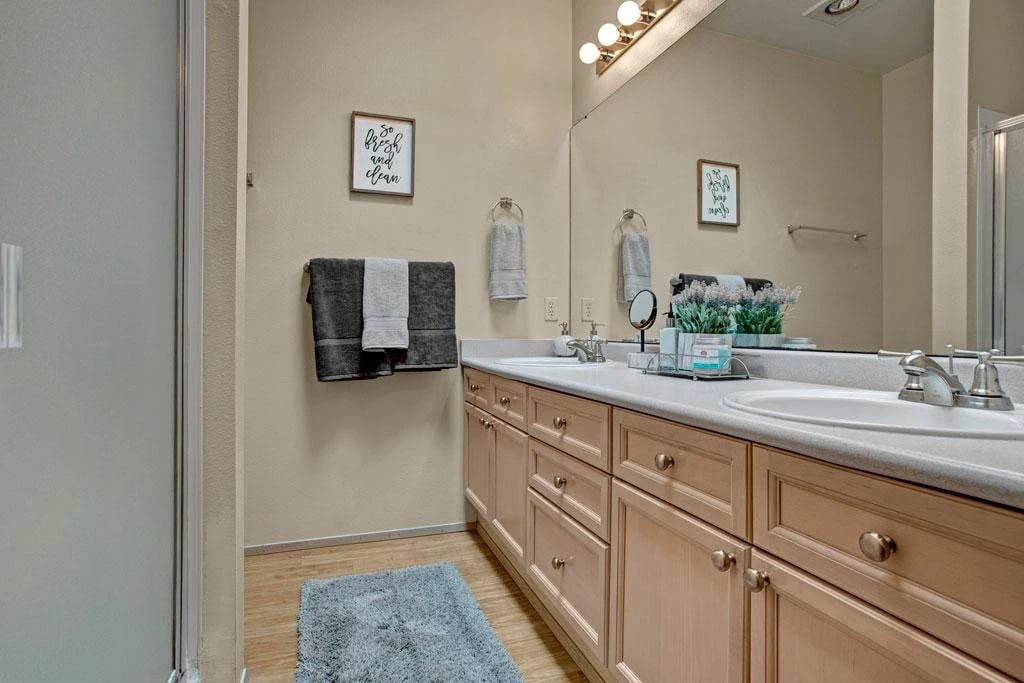Modern bathroom with double vanity, large mirror, and shower.