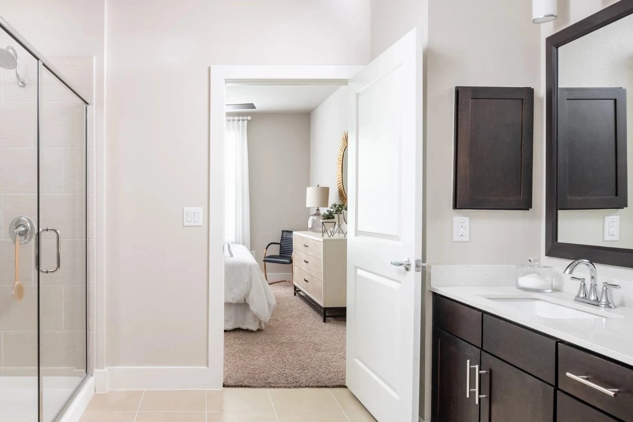 Modern bathroom with glass shower and view into bedroom