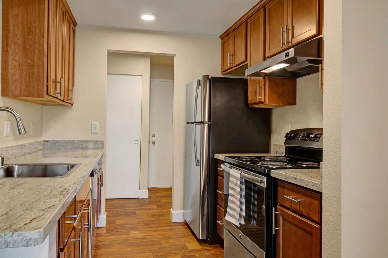 Modern kitchen with stainless steel appliances, granite countertops, and wood cabinets.