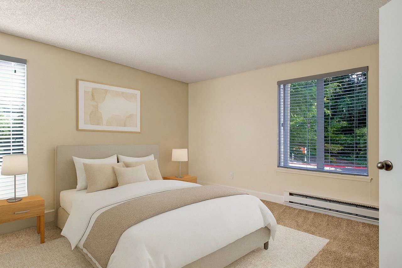 Bedroom with a queen-size bed, two nightstands, and a window overlooking trees.