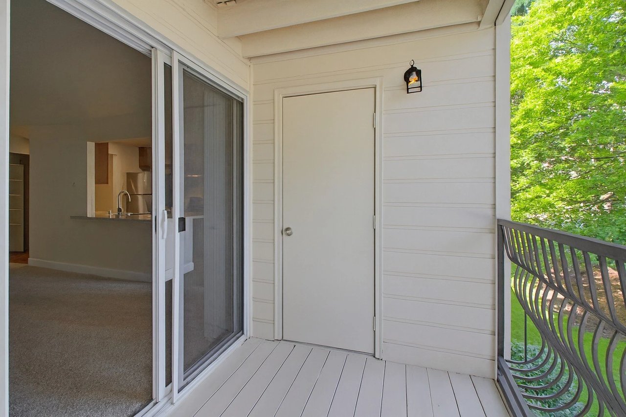 Balcony with sliding glass door leading into apartment interior and a storage closet door.