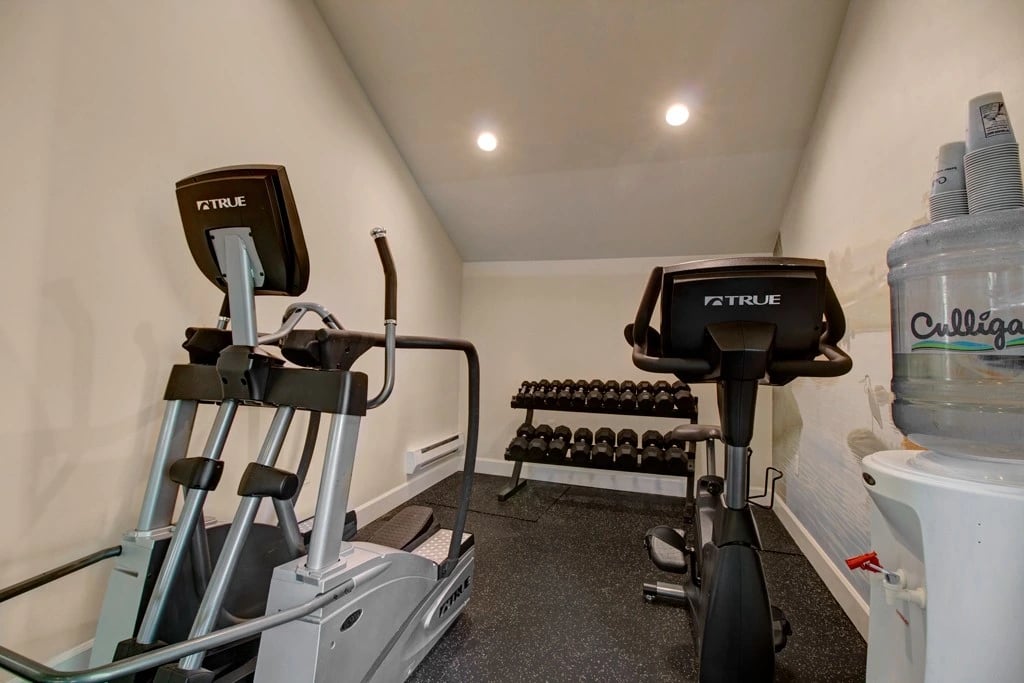 Gym with cardio machines, free weights, and water cooler.