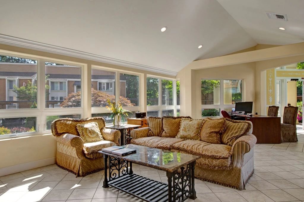 Comfortable seating area with sofa, armchair, and coffee table overlooking exterior building.