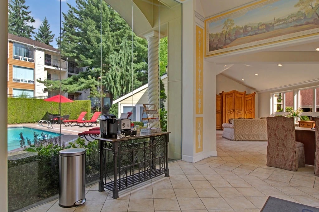 Outdoor swimming pool with lounge chairs and umbrellas, adjacent to apartment buildings.