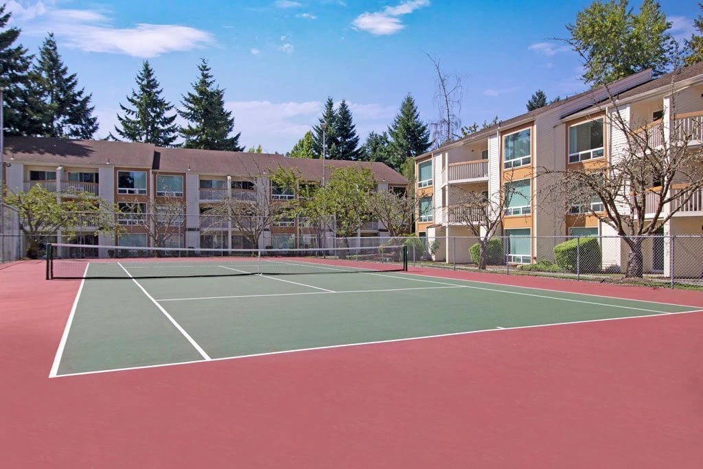 Tennis court with apartment buildings in the background.