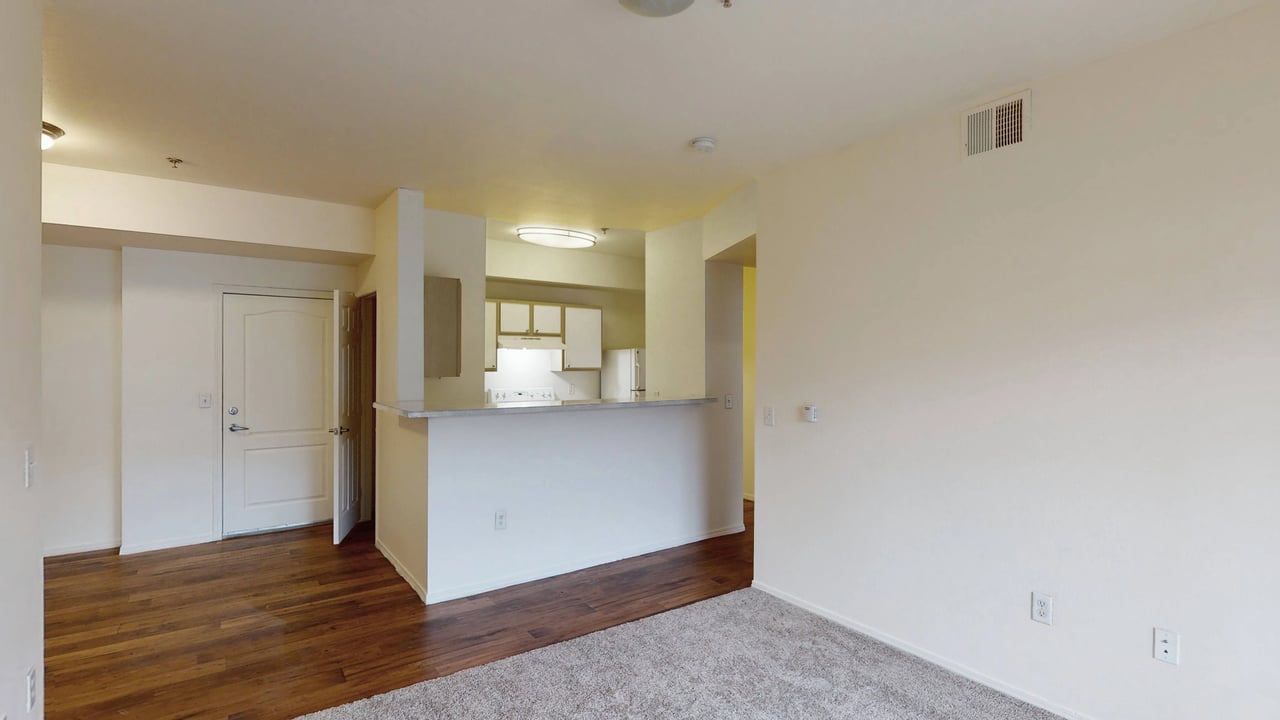 Empty apartment living room and kitchen area with a breakfast bar.