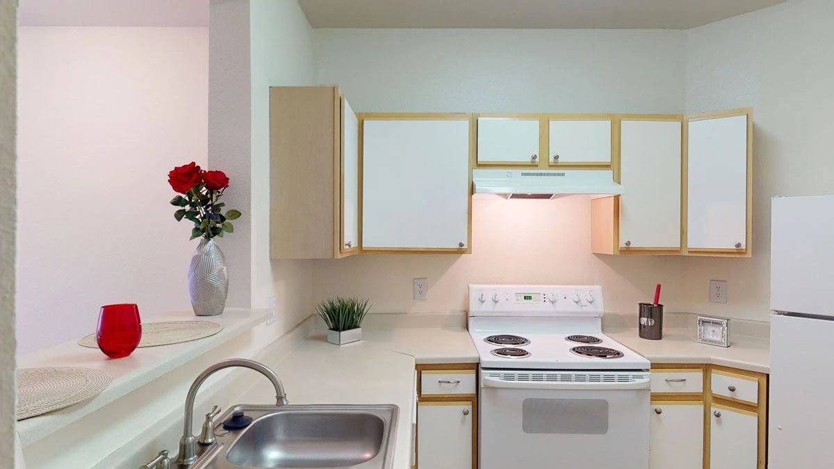 Kitchen with white cabinets, white stove, and stainless steel sink.