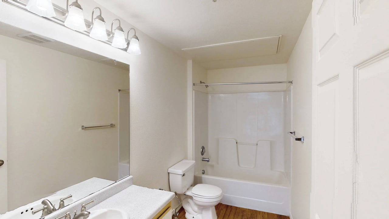 A clean and bright bathroom with a vanity, toilet, and bathtub.