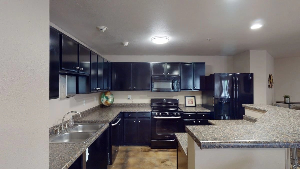 Modern kitchen with dark cabinets, granite countertops, and stainless steel sink.