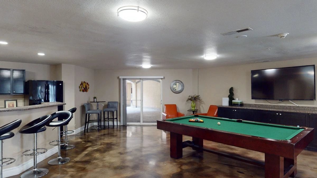 Community lounge with a pool table, bar seating, and a TV.