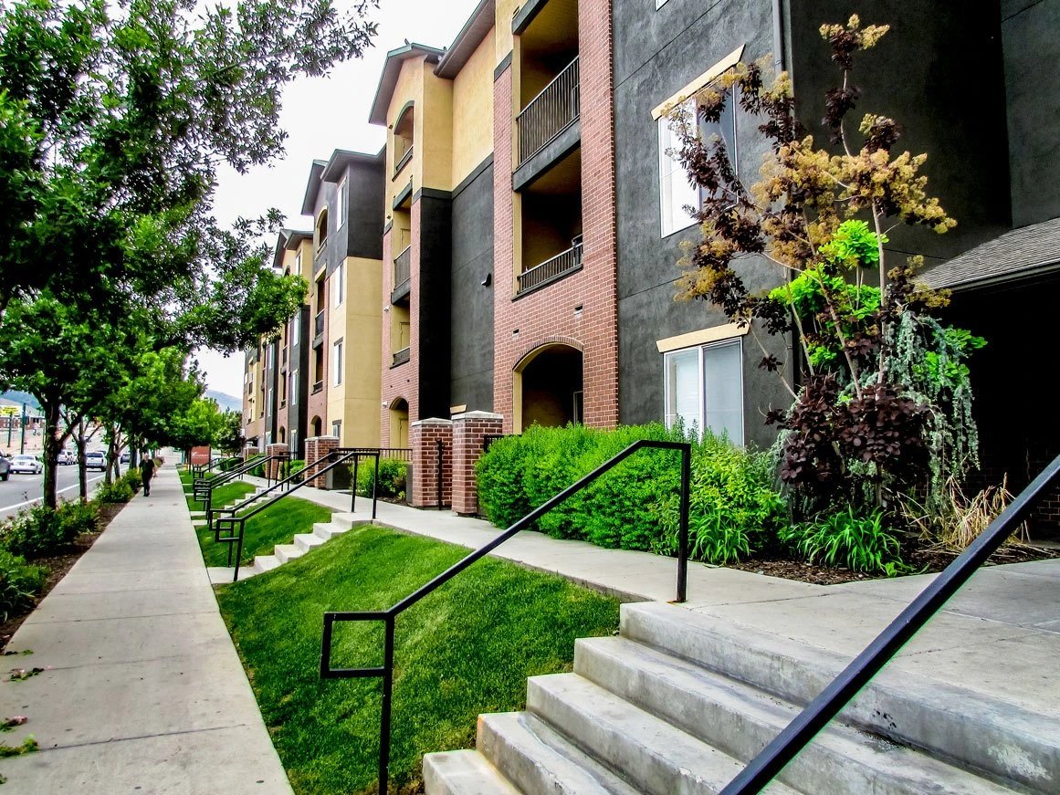 Exterior view of an apartment building with a sidewalk and stairs.