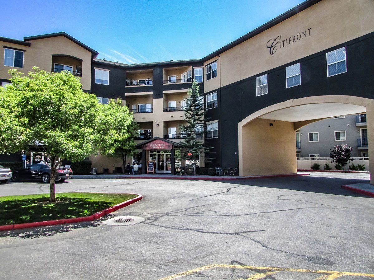 Citifront apartment building exterior with a large arched entrance and a tree in the foreground.