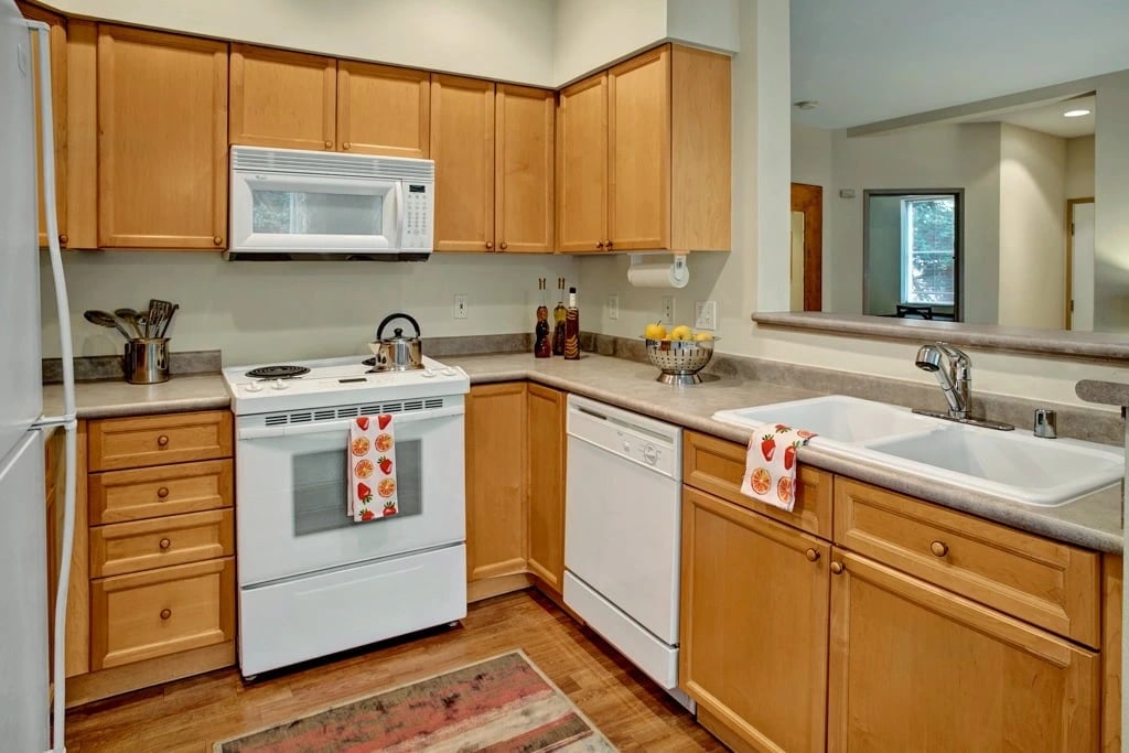 Kitchen with light wood cabinets, white appliances, and granite countertops.
