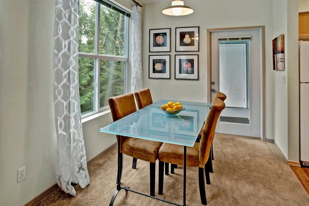 Dining area with a glass-top table and four upholstered chairs.