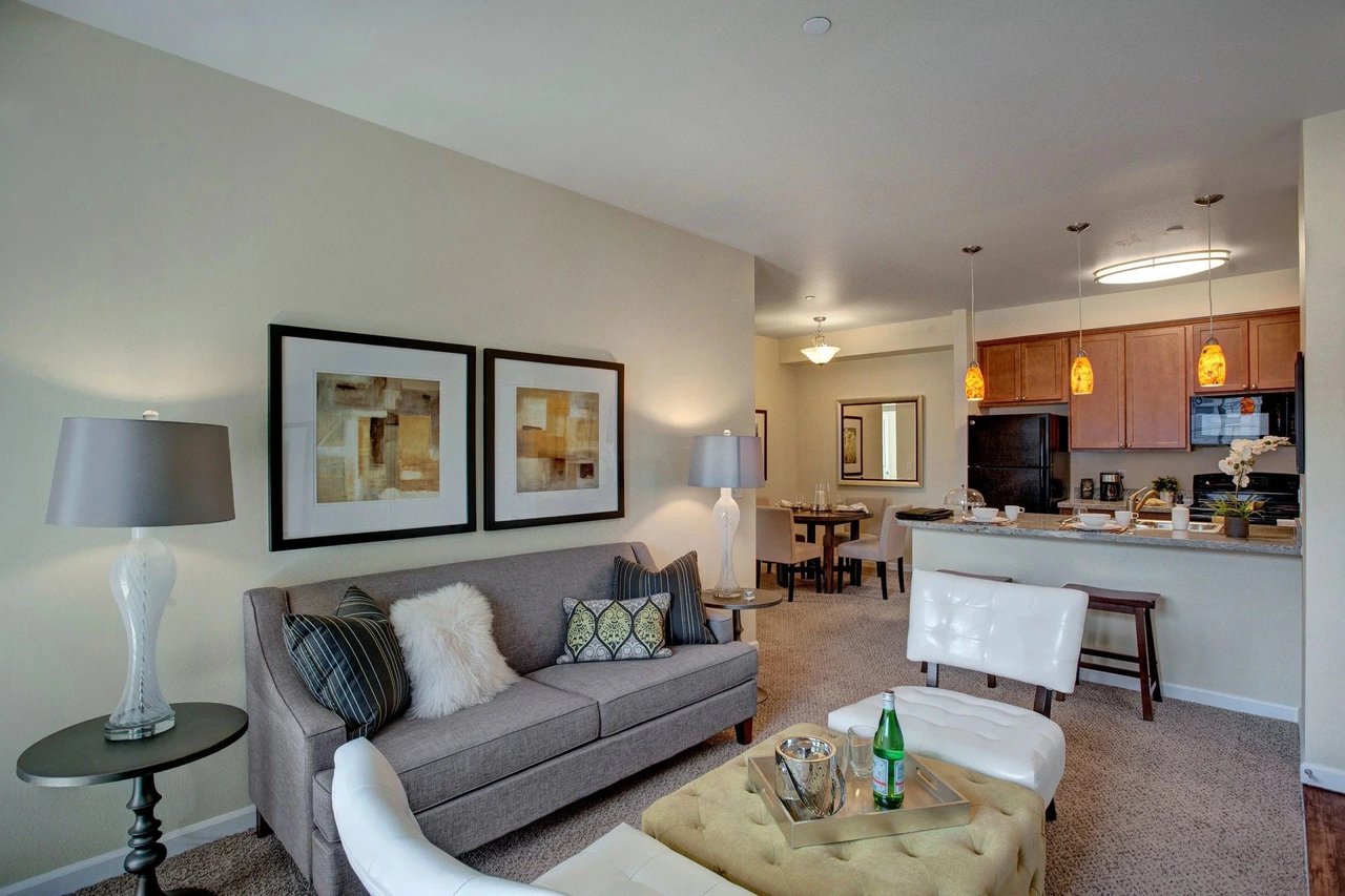 Living room with sofa, coffee table, and dining area, open to kitchen.