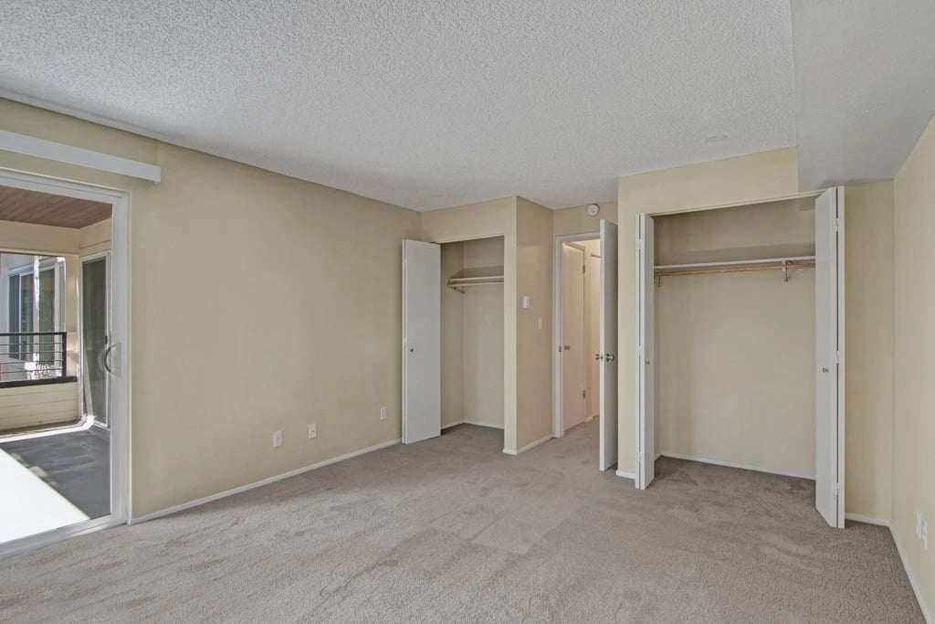 Empty bedroom with two closets and balcony access.