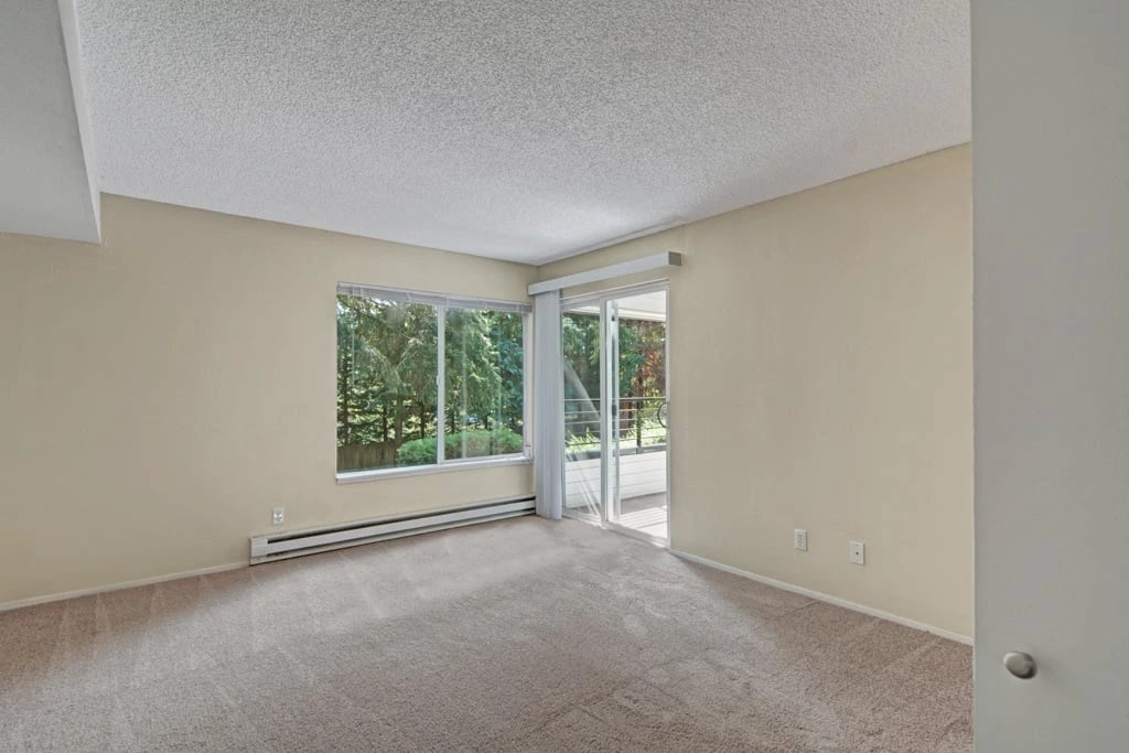 Living room with large window and sliding glass door overlooking trees