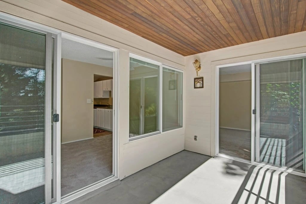 View from a sunroom or enclosed patio looking into a kitchen and living area.