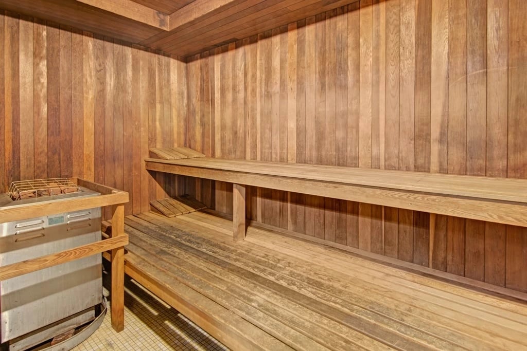 Wooden sauna with tiered benches and a heater.