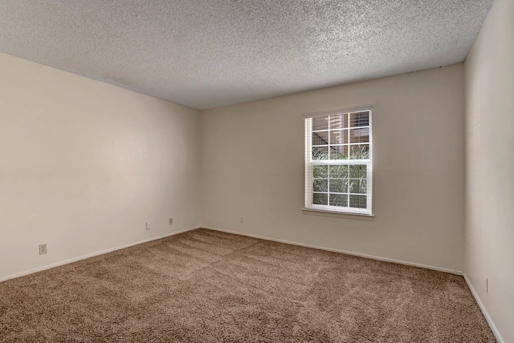 Empty bedroom with carpet and a window.