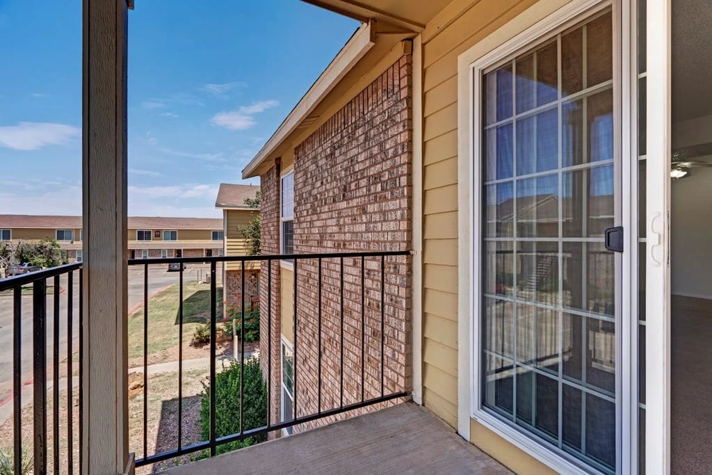 View from balcony overlooking apartment complex buildings and parking lot.