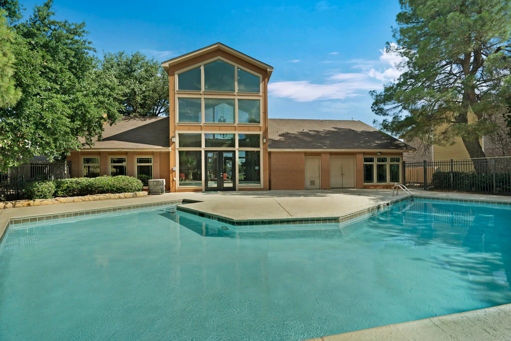 Outdoor swimming pool with lounge area and building.