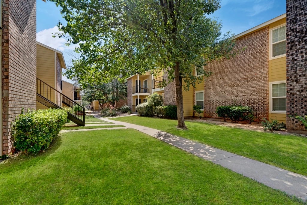 Apartment buildings with green grass and walking path.