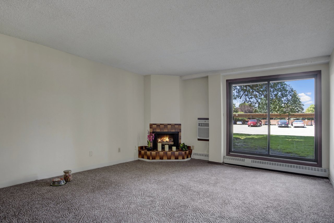 Living room with a corner fireplace and a large window overlooking the parking lot.