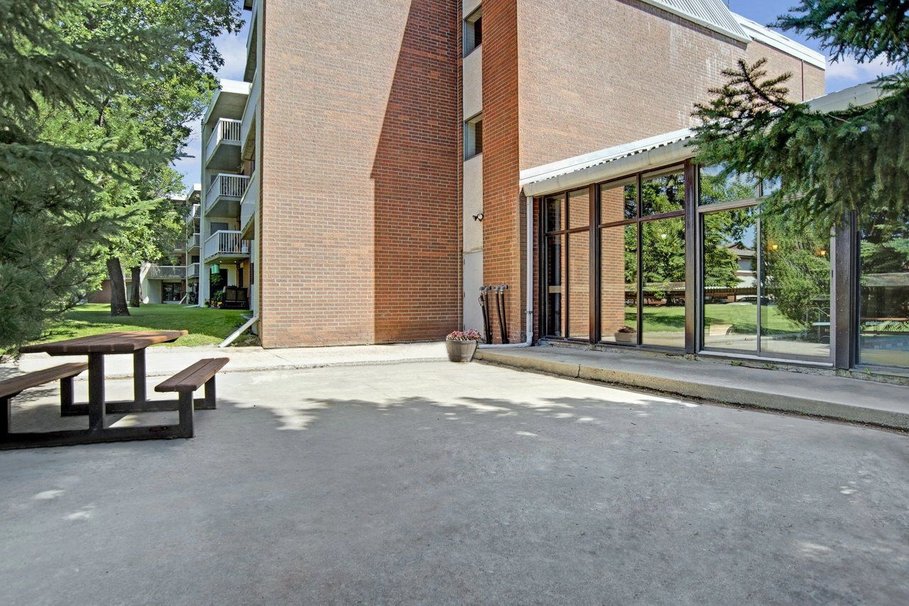 Exterior view of apartment building with picnic table and green space.