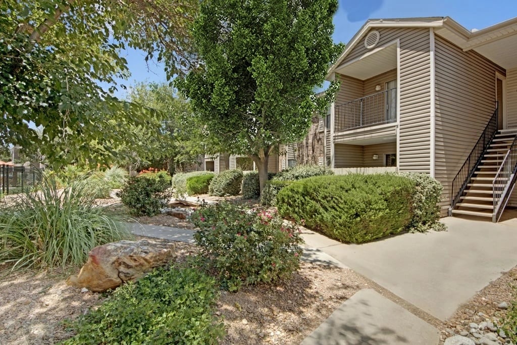 Apartment building exterior with exterior stairs and landscaping.