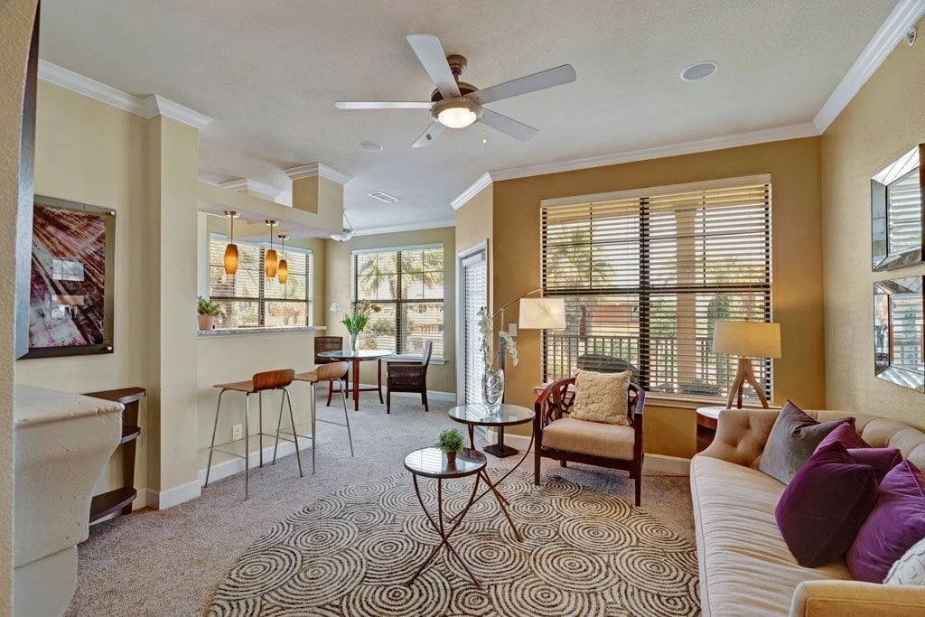 Living room and dining area with a sofa, armchair, coffee table, and bar seating.