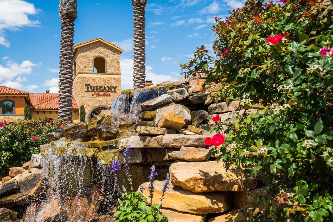 Tuscany at Hunters Creek building entrance with a waterfall and lush greenery.