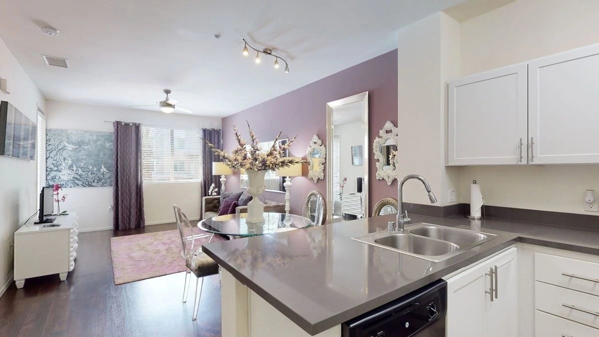 Modern kitchen and living area with purple accent wall and stylish furniture.