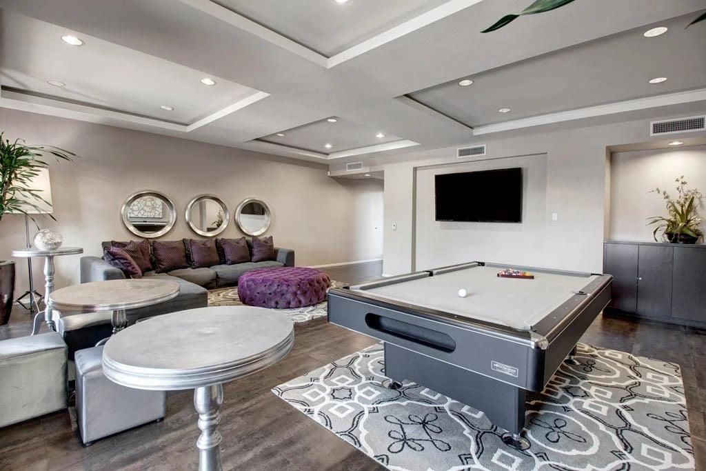 Comfortable lounge area with a pool table, sectional sofa, and decorative mirrors.