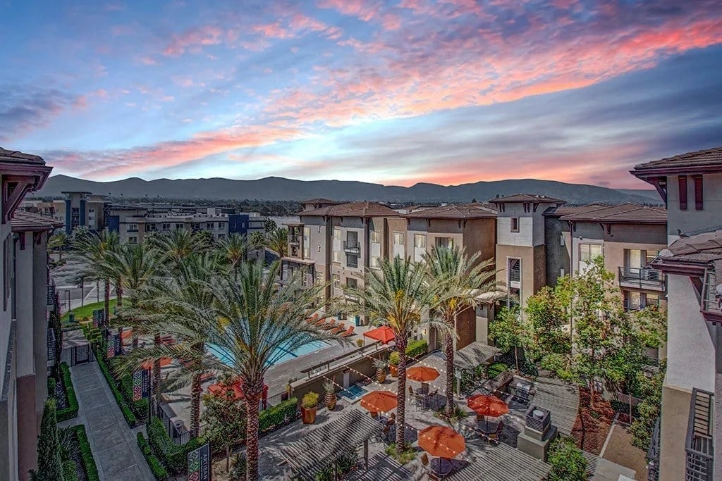 Apartment complex courtyard with pool and seating areas at sunset.