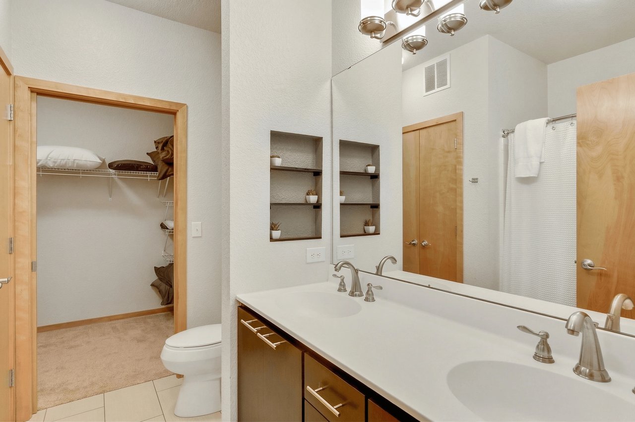 Modern bathroom with double vanity, large mirror, and walk-in closet.
