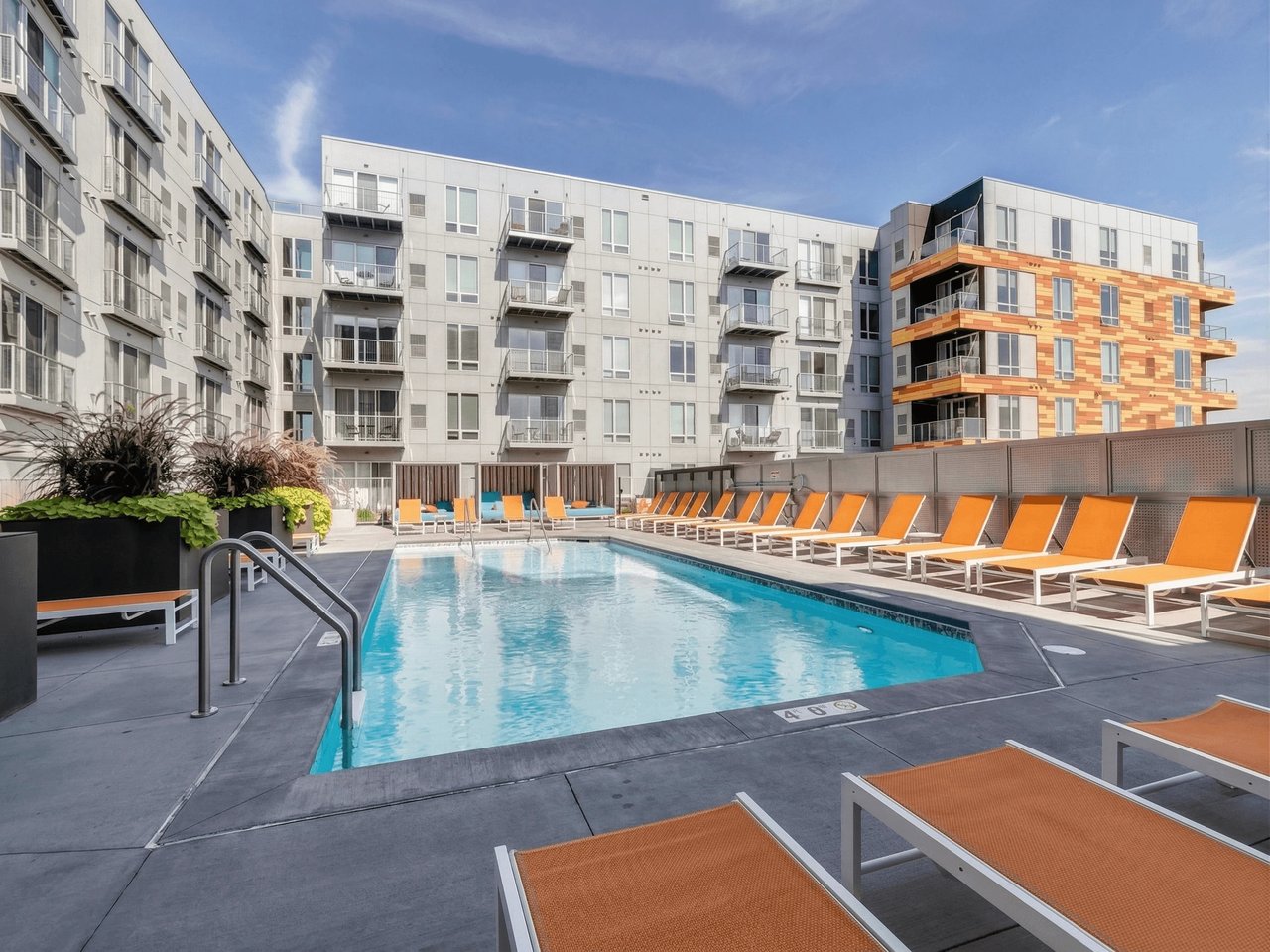 Apartment complex outdoor swimming pool with lounge chairs.