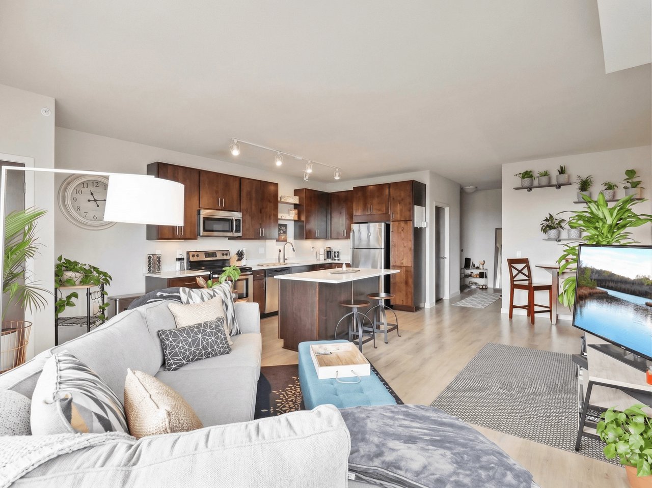 Modern living room and kitchen area with comfortable sofa, large TV, and island.