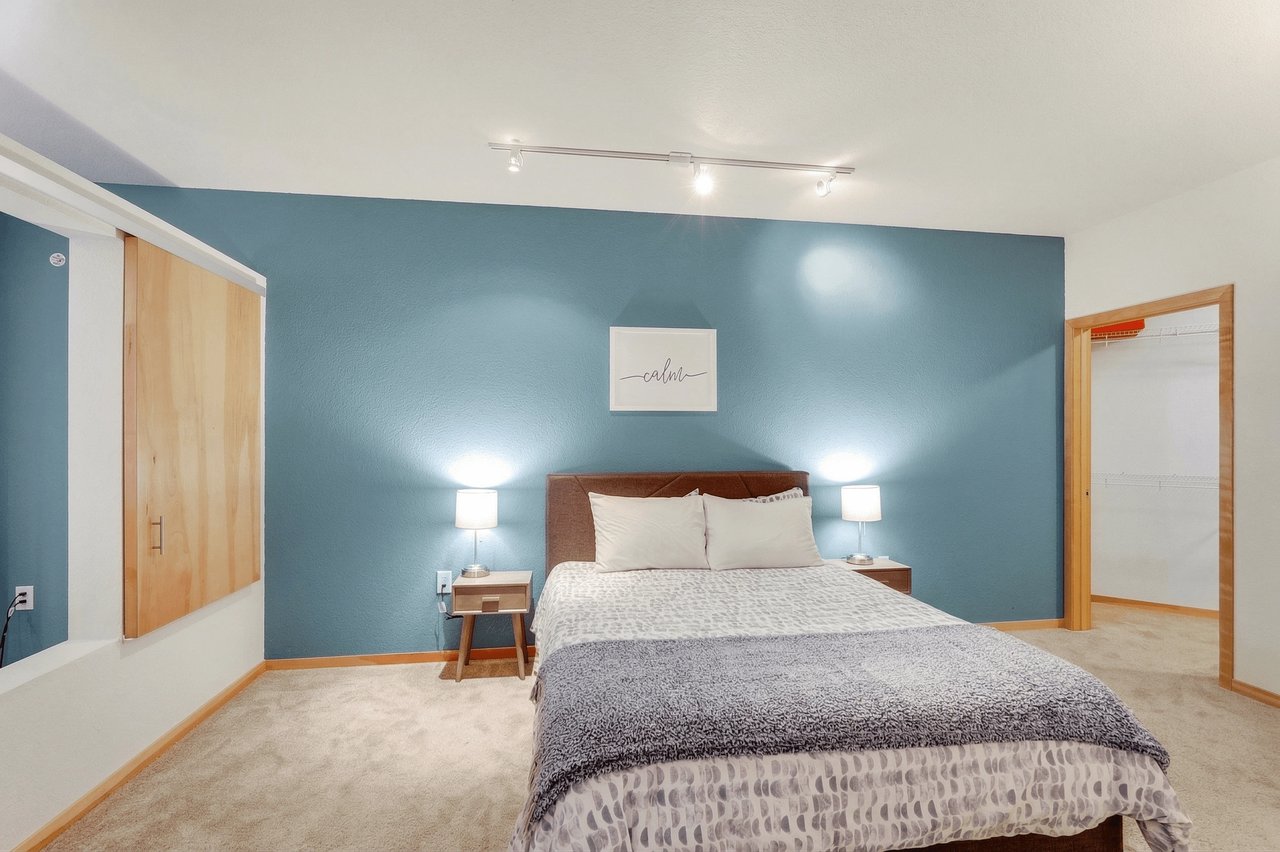 Bedroom with a queen-size bed, blue accent wall, and a walk-in closet.