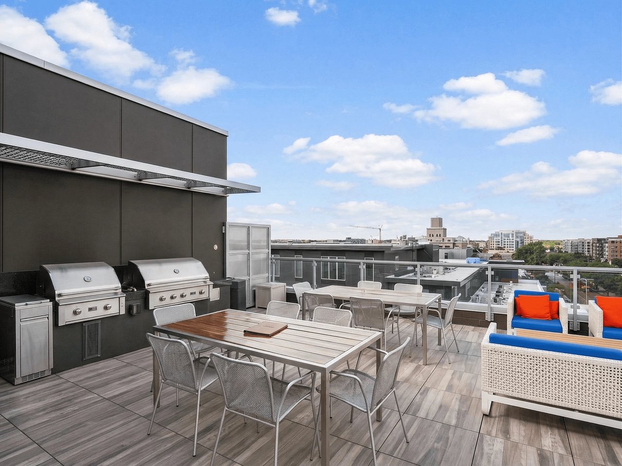 Outdoor patio with grills, dining tables, and lounge seating overlooking city skyline.