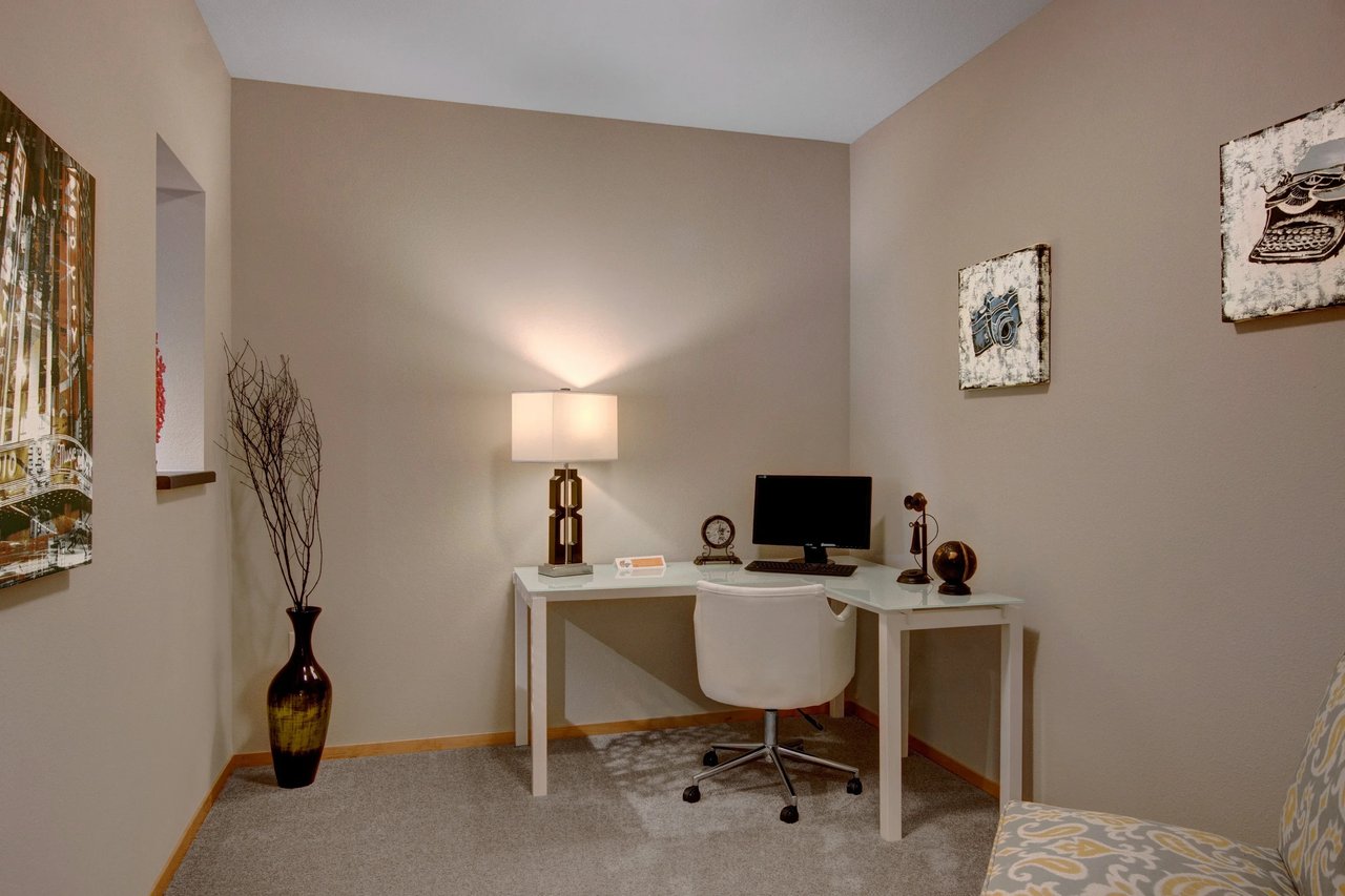 Home office nook with a glass desk, chair, and computer.