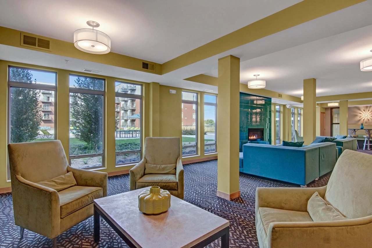 Interior community lounge with multiple seating areas, large windows, and a fireplace.