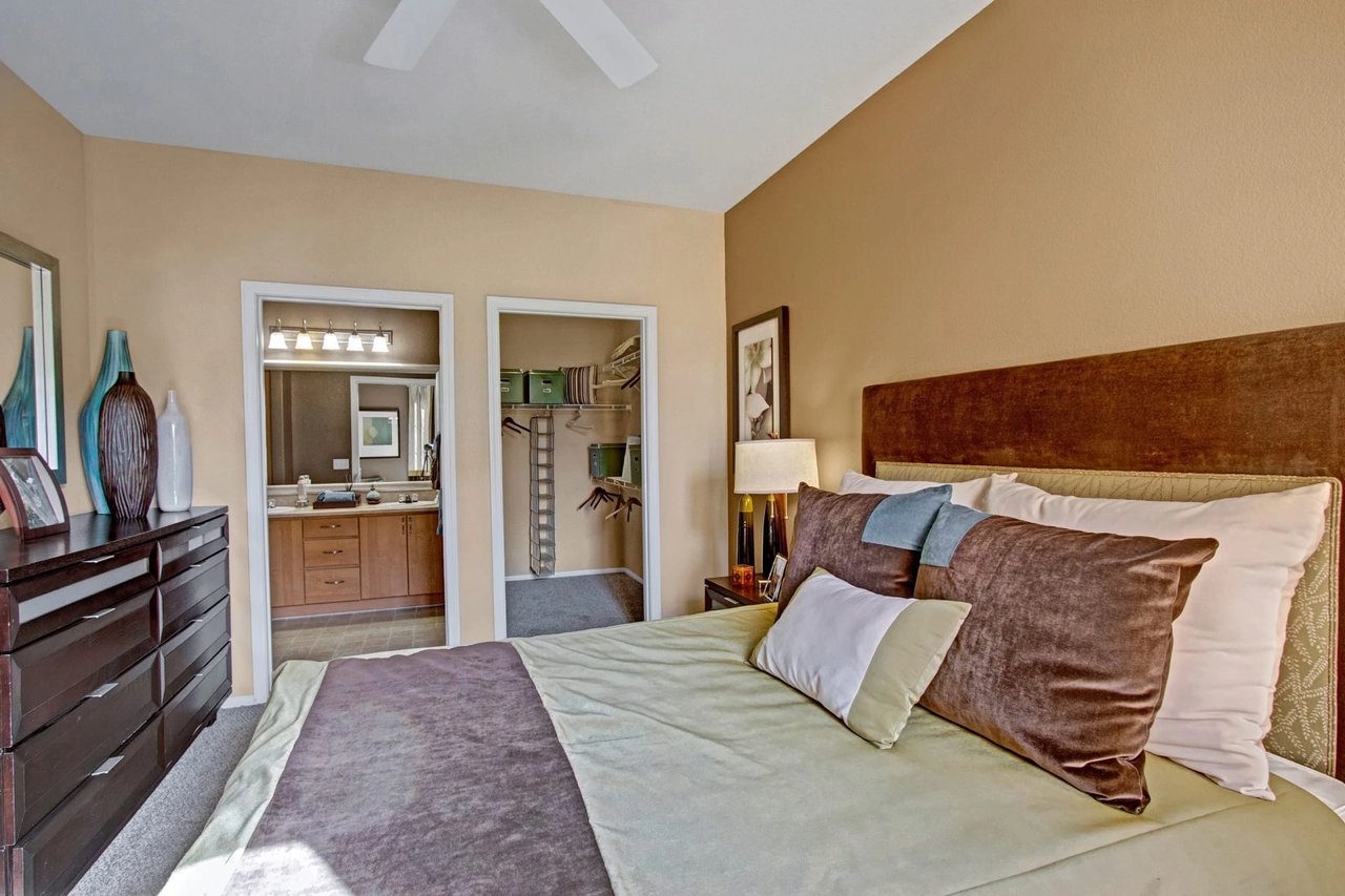 Bedroom with a large bed and a view into the bathroom and closet.