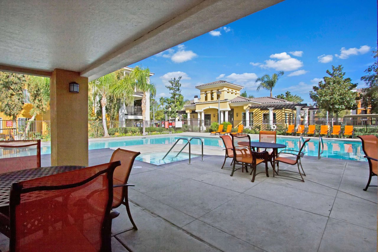 Outdoor swimming pool and patio area with tables and chairs.