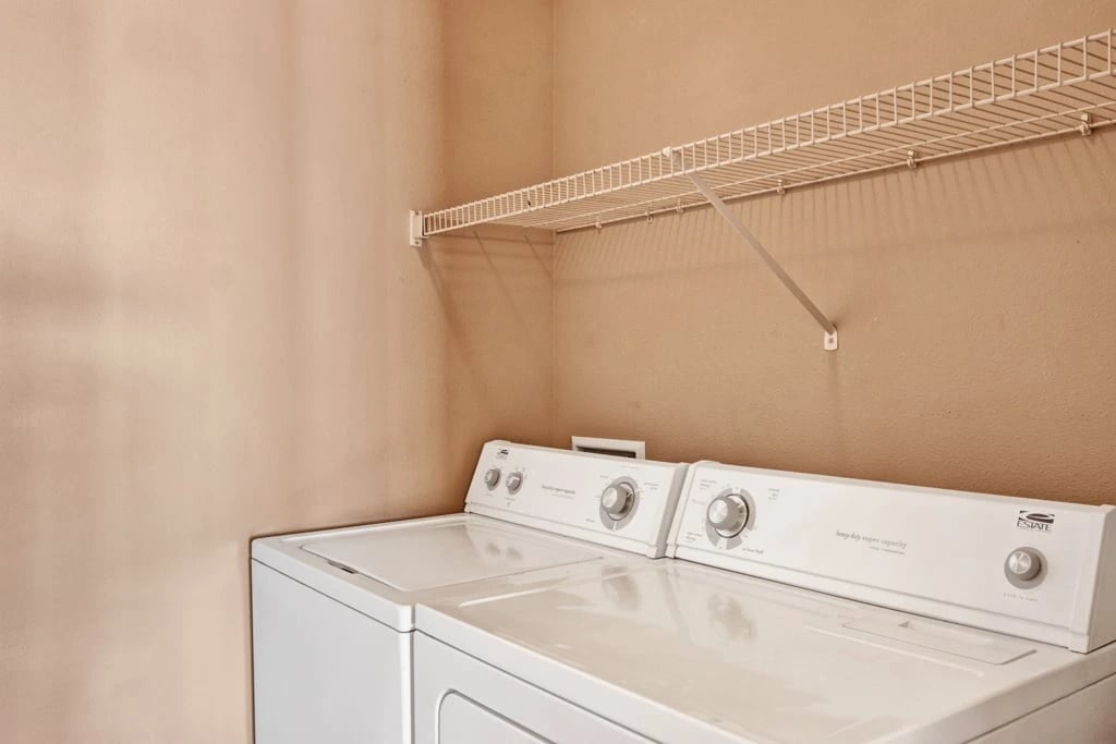 White stacked washer and dryer with a shelf above.